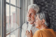 © Daniel - Pensive elderly mature senior man in eyeglasses looking in distance out of window, thinking of personal problems. Old woman wife consoling and hugging sad husband, copy space.