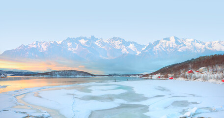 Wall Mural - beautiful winter lanscape with cracks on the surface of the turquoise (green) ice next to snowy moun