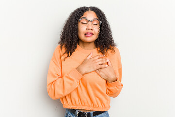 Wall Mural - Young african american woman isolated on white background has friendly expression, pressing palm to chest. Love concept.