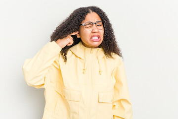 Wall Mural - Young african american woman isolated on white background covering ears with fingers, stressed and desperate by a loudly ambient.