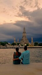 Wall Mural - Couple at Wat Arun temple in Bangkok Thailand during sunset.