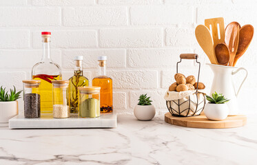 Wall Mural - several bottles of butter for cooking and kitchen utensils in the modern kitchen on a white marble countertop. brick wall. front view.