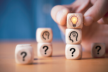 Poster - hand putting wooden cube block stacking which print screen glowing light bulb and question mark with