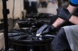 Employee of a car detailing studio applies a protective ceramic coating to a car rim