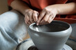 Close up of female hands molding wet clay on wheel, shaping final pottery product, potter making unique handmade stoneware, selective focus. Stress-relieving hobbies, ceramics and mental heath