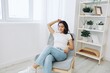 © SHOTPRIME STUDIO - Woman sitting in a chair listening to an audiobook on wireless headphones at home in jeans and a white T-shirt, fall lifestyle comfort