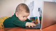 © guruXOX - Portrait of baby boy using a laptop computer at his business office - game room. Technology and toys concept. Funny babies