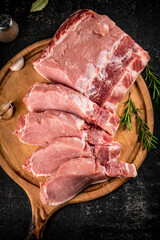 Canvas Print - Fresh raw pork on a cutting board with rosemary.