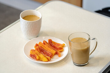 Sticker - Dried papaya on a white plate standing on the table, next to two cups of coffee with milk. 