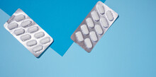Oval White Pills In A Gray Blister Pack On A Blue Background, Top View.