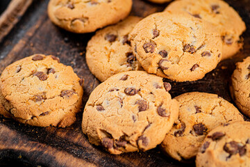 Sticker - Pile of homemade cookies with pieces of milk chocolate on the table.