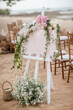 A welcome board sign with a beautiful flower decoration, standing in front of wedding entrance on the beach
