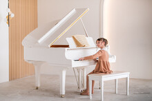 A Little Girl Plays A Big White Piano In A Bright Sunny Room