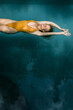 © Evgenii - A beautiful girl in a yellow swimsuit swims on her back in the pool, top view.