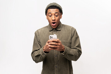 Funny surprised trendy guy suddenly read message on his mobile phone and expressing shock amazement, unbelievable news on smartphone. Studio shot isolated