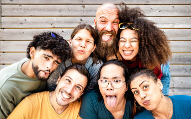 Wall Mural - Young friends taking selfie making funny face expression - Happy life style concept with millenial people having fun together - University college students sharing story on social media network