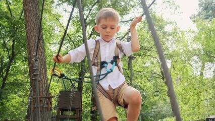 Wall Mural - Portrait of little boy crossing obstacles at outdoor climbing training park. Active childhood, healthy lifestyle, kids playing outdoors, children in nature