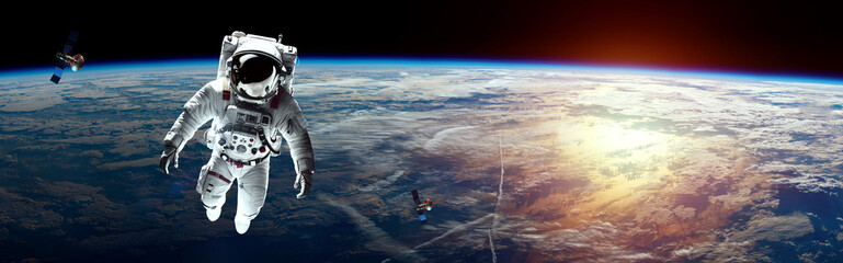 Wall Mural - an astronaut in a white spacesuit hanging in space against the backdrop of planet earth. copy space