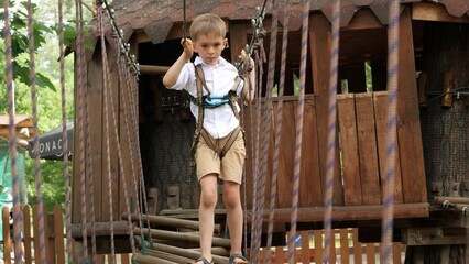 Canvas Print - Little boy holding safety rope and crossing wobbly bridge at summer camp. Kids sports, summer holiday, fun outdoors, scouts