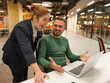 A red-haired Caucasian woman stands at the desktop of a bearded man. The boss approves the work of the subordinate. 
