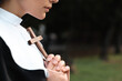 © New Africa - Young nun with Christian cross in park outdoors, closeup. Space for text