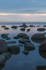 Wall Mural - Blue hour after the sunset over rocky Baltic sea cost. Small stones and big boulders in the sea. Long exposure photo.