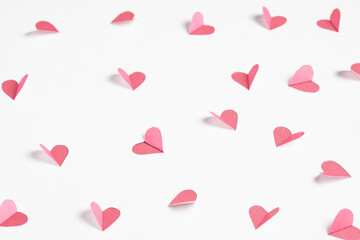 Pink hearts cut out from white paper. Festive background for valentine's day.