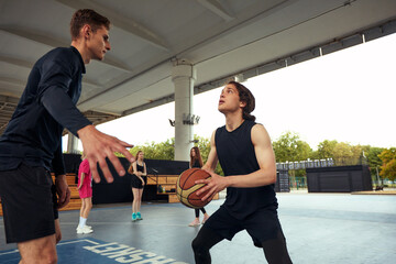 Young guys playing basketball, posing for the camera on the city basketball court, lifestyle active leisure young people.