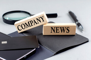 Poster - COMPANY NEWS text on wooden block on black notebook , business concept