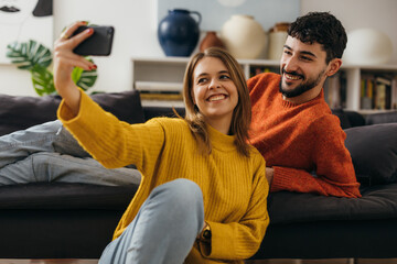 Wall Mural - Young caucasian couple taking a photo together with a front camera