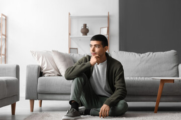 Canvas Print - Thoughtful young man sitting on sofa at home