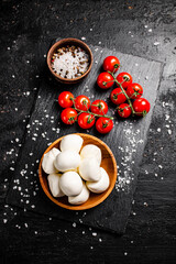 Poster - Mozzarella cheese in a plate on a stone board with tomatoes and spices.