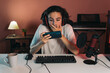 gamer guy playing video games in his smartphone with surprise gesture in his bedroom