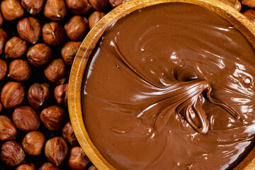 Poster - Hazelnut butter on a wooden plate with peeled hazelnuts.