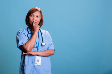 Pensive medical assistant wearing blue uniform thinking about health care treatment to cure sick patient during appointment. Thoughtful nurse brainstorming ideas, doubt expression. Medicine concept