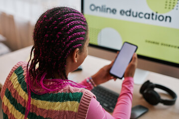 Wall Mural - Black teenage girl using smartphone at desk against online education website