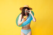 © Богдан Маліцький - young shocked brunette girl in a blue swimsuit with a swimming inflatable ring holds a smartphone