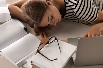 Wall Mural - Young tired woman sleeping near books at table