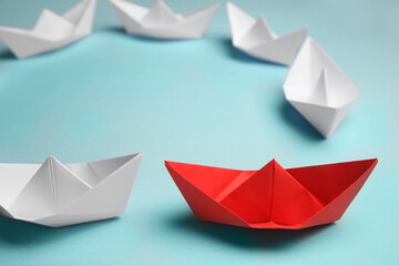 Canvas Print - Group of paper boats following red one on light background. Leadership concept