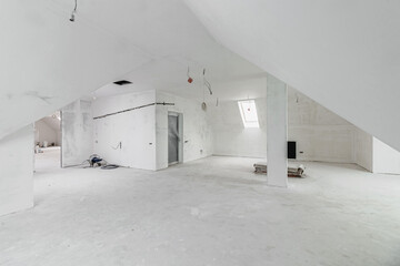 Spacious empty rooms in the attic floor after filling out the work on the wall and ceiling