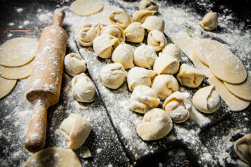 Poster - Raw homemade dumplings on a cutting board with a rolling pin. 