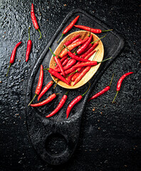 Canvas Print - Pods of hot chili peppers on a cutting board.