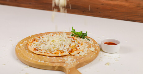 Closeup studio shot hot baked tasty delicious Italian homemade ham pineapple original Hawaiian soft bread crust pizza on wooden plate pan while sprinkle mozzarella cheese on top with tomato ketchup