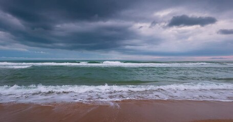 Wall Mural - Morning dark clouds over the ocean beach shore. Dramatic cloudscape and sea waves rolling on the sand