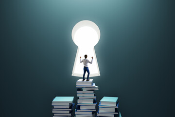 Education and knowledge concept with happy man back view looking at the window in form of key hole staying on book stacks on dark background