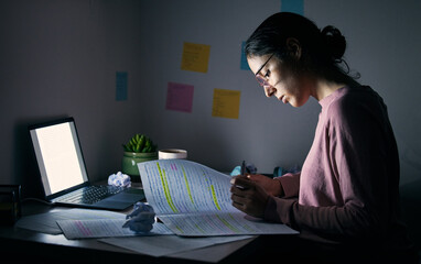 student, reading notebook and studying at night with laptop of learning, education or internet proje