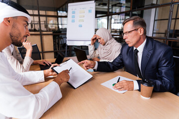 Multiracial group of corporate businesspeople working in a business office - Multiethnic businessmen and businesswomen meeting in the office in Dubai, UAE