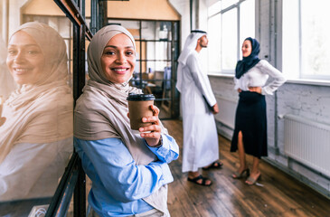 Wall Mural - Middle-eastern group of corporate businesspeople working in a business office - Arab businessman with kandora and businesswomen with abaya meeting in the office in Dubai, UAE