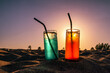 Refreshing tropical alcoholic coctails with straws and colorful sunset sky at background