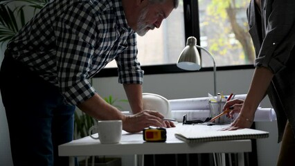 Wall Mural - Two cropped architects discussing floor plan at table in office. Design of the house. Engineer. Tools for drawing. Creating a drawing.